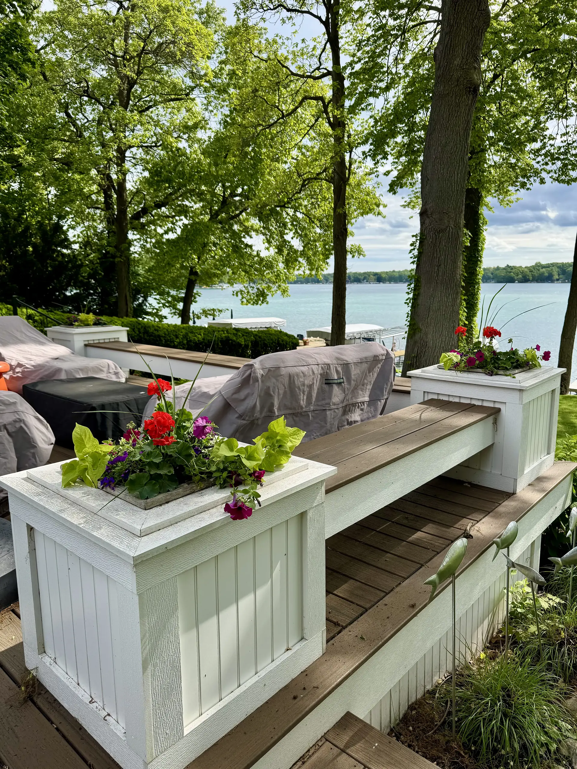 White planters with red geraniums on a lakefront deck